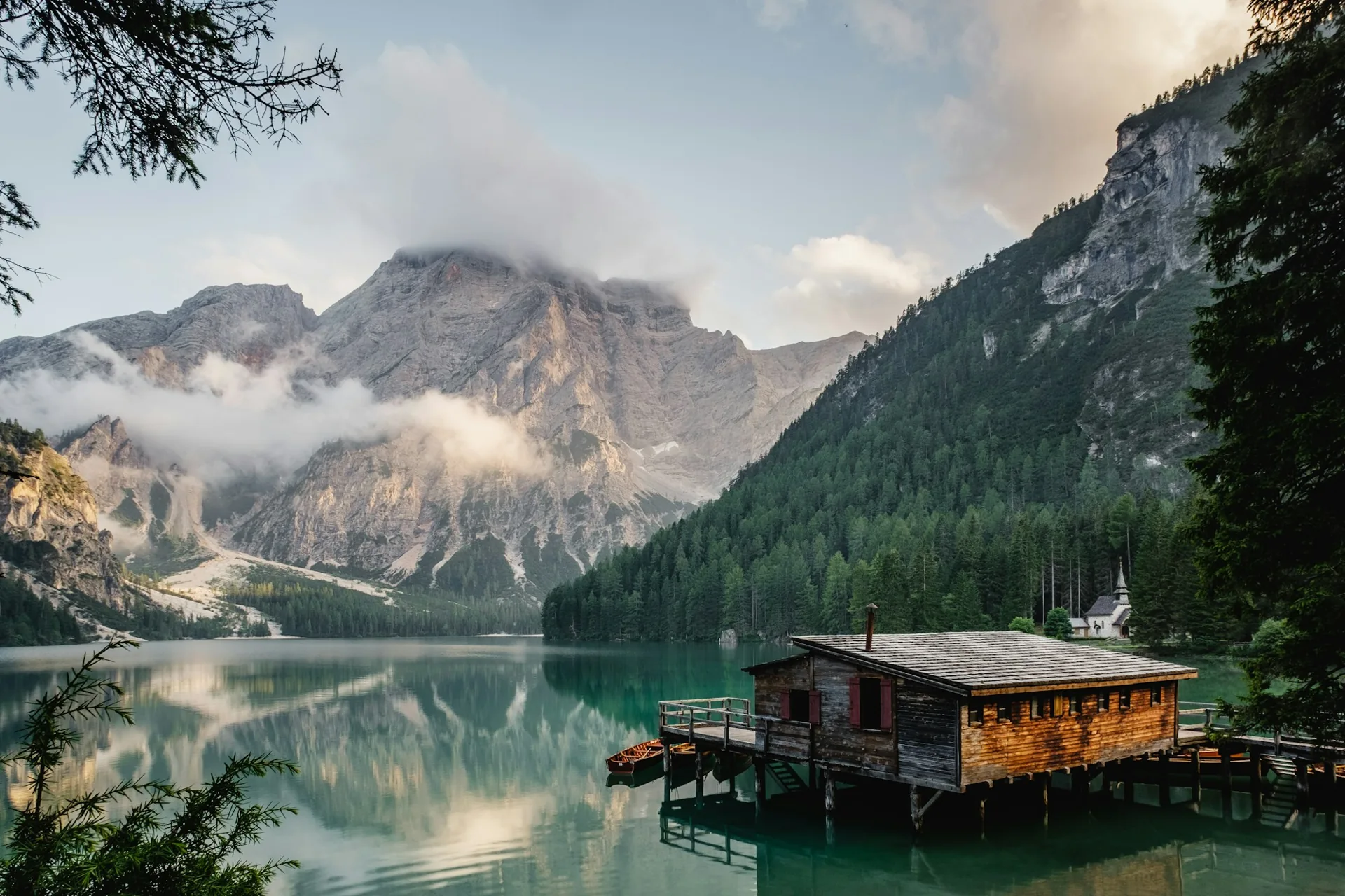 Still alpine lake reflecting mountains and a small waterside cabin